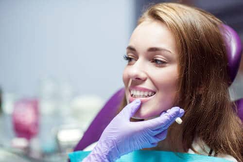 Dentist examining women after getting brandon fl dental crowns put on her teeth.