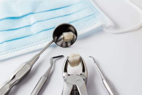 Dentist tools holding a tooth after a tooth extraction procedure.