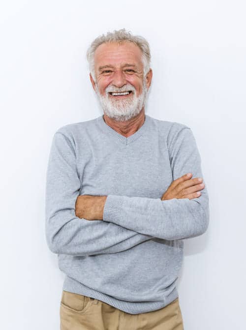 A mature man wearing a gray sweater smiling
