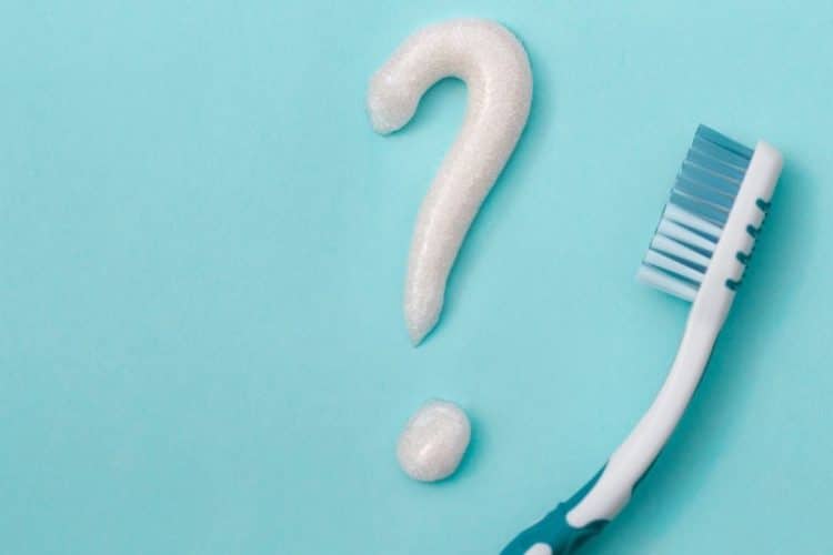 A toothbrush with a question mark made of toothpaste