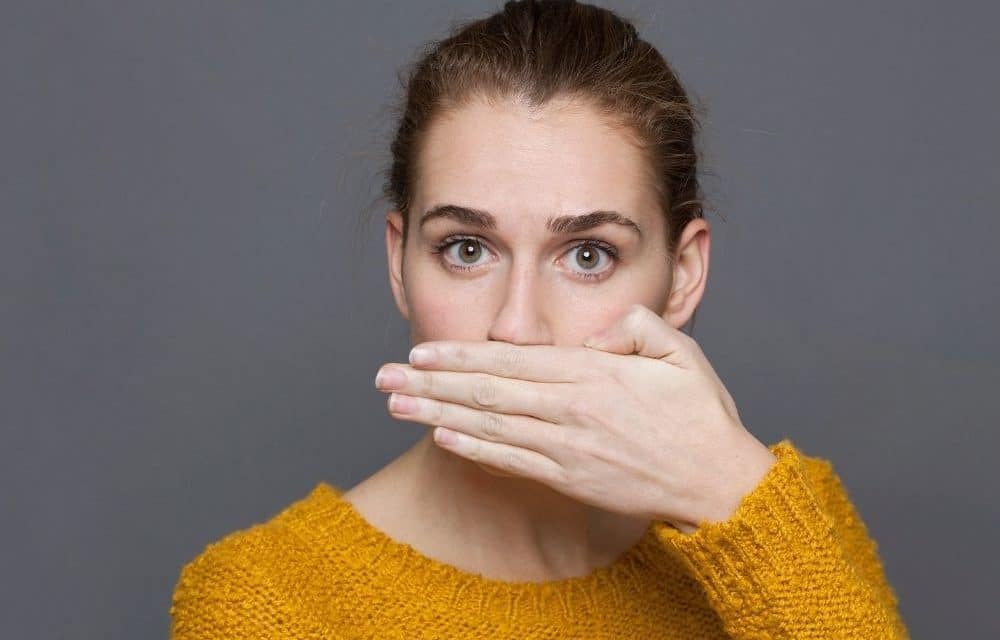 A woman putting her hand over her mouth because of bad breath