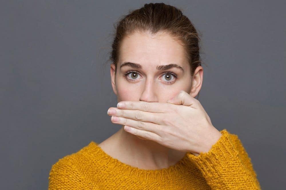 A woman putting her hand over her mouth because of bad breath