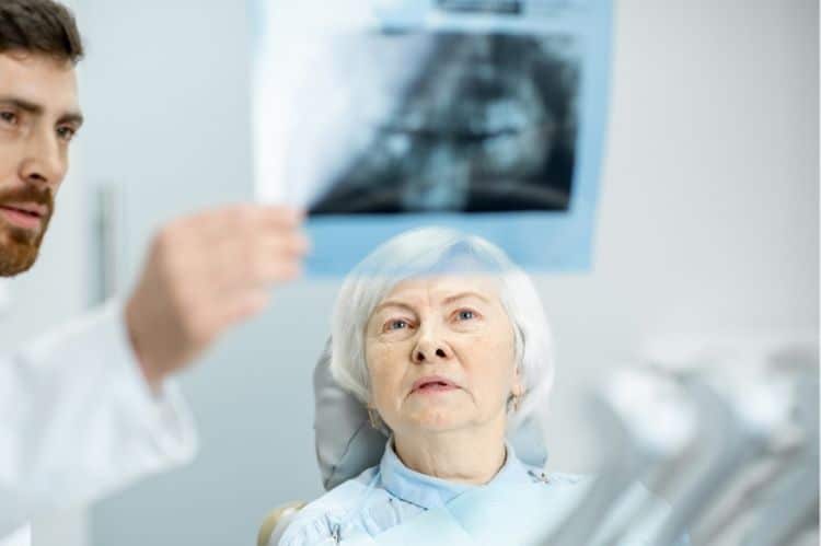 An older woman reviewing her teeth x ray with her dentist before getting a dental implant