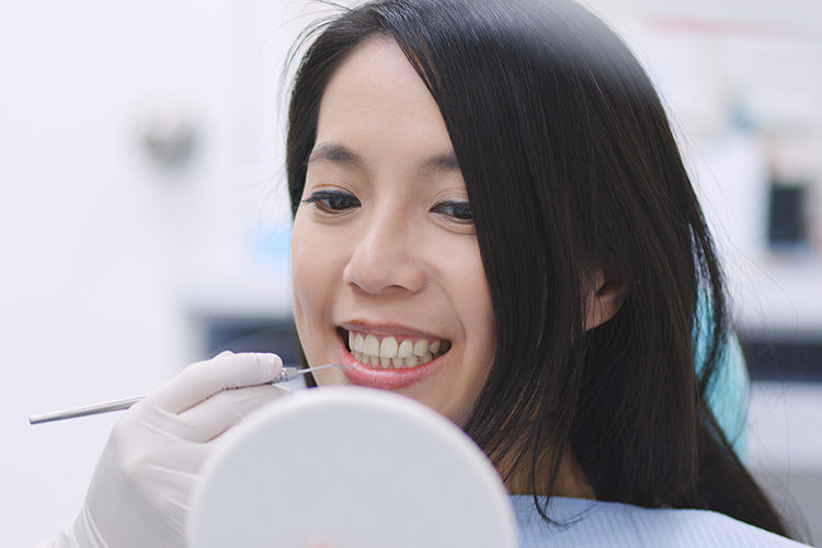 Woman making sure she has no tooth decay under her fillings